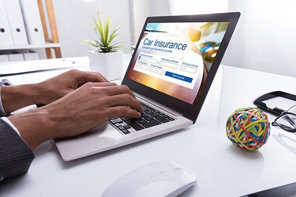 Businessperson Filling Car Insurance Form on Laptop — Chicago, IL — Illinois Insurance Center Inc