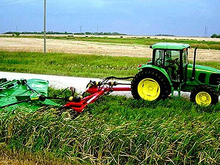 一种连接在约翰迪尔拖拉机上的手动悬挂式补偿割草机正在割一片草地
