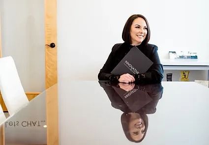 A woman is sitting at a table holding a book.