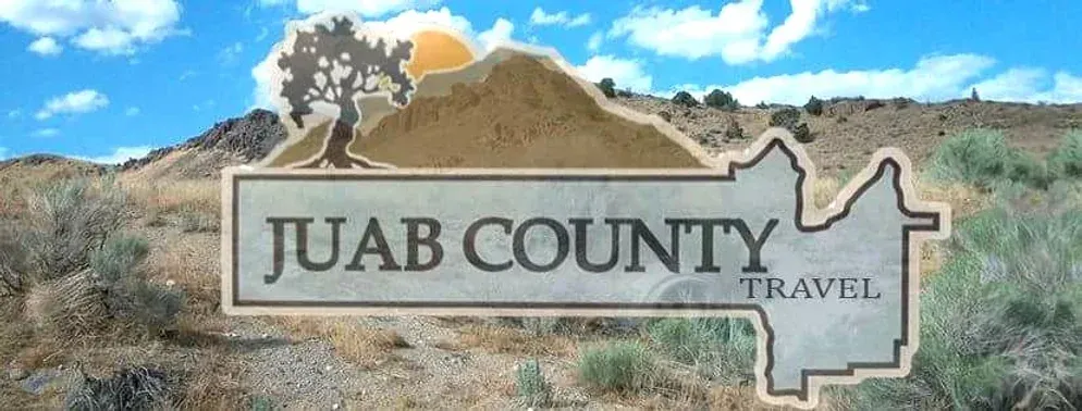 A sign for juab county travel with a mountain in the background