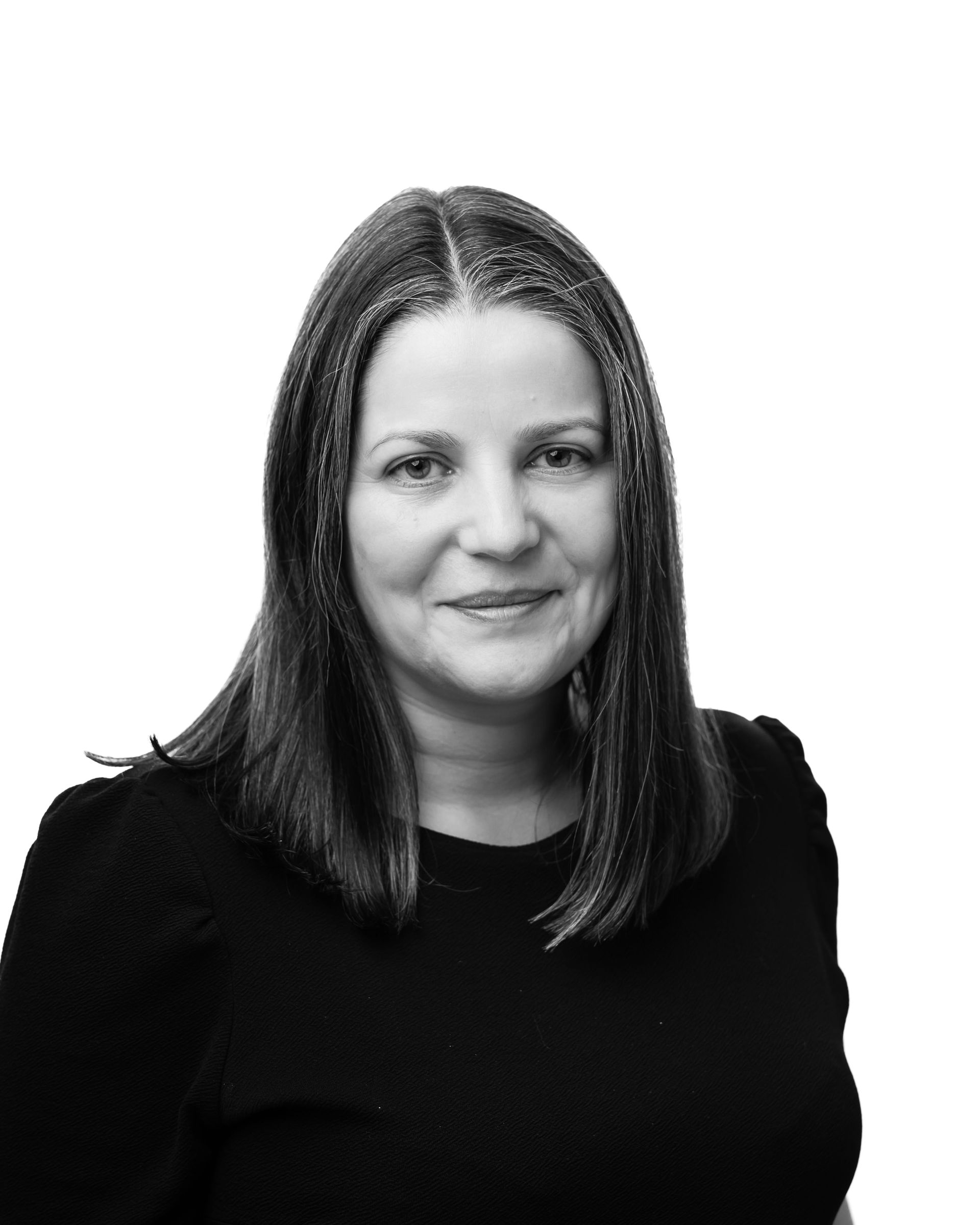 A woman in a black shirt is smiling in a black and white photo.