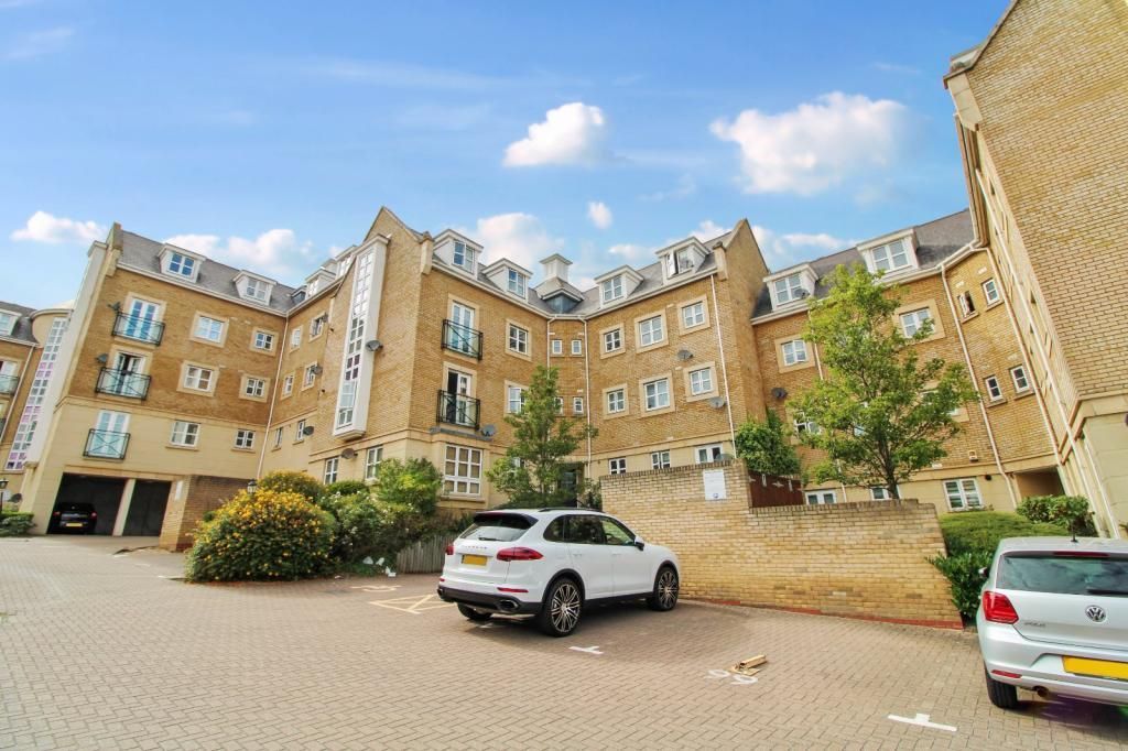 A white car is parked in front of a large apartment building.