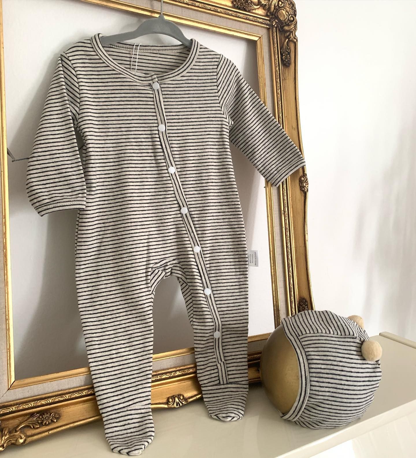 A Baby's Onesie and A Hat Are Hanging on A Hanger Next to A Picture Frame - Saint Georges, DE - Chavies Boutique