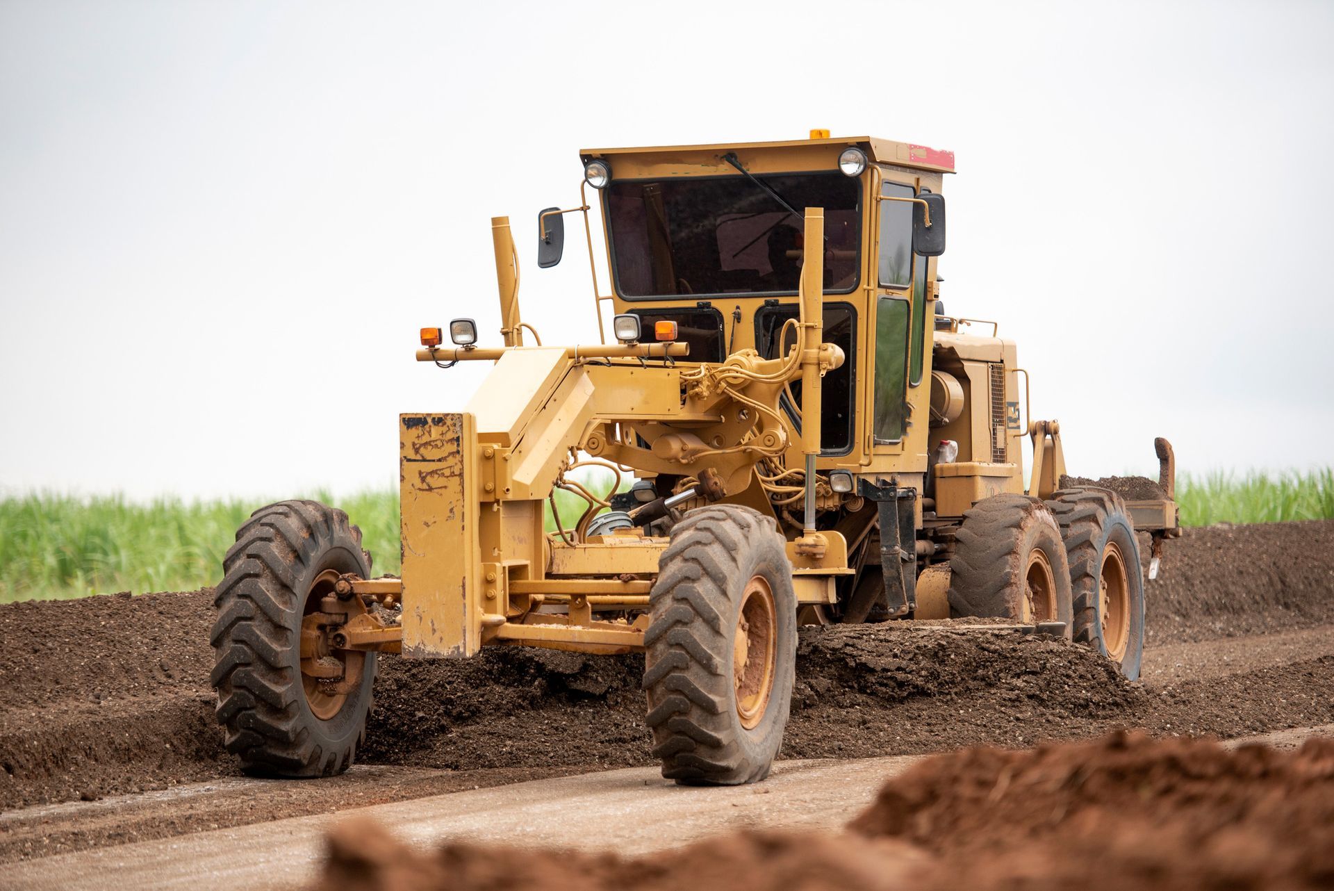 Yellow tractor on a dirt road.