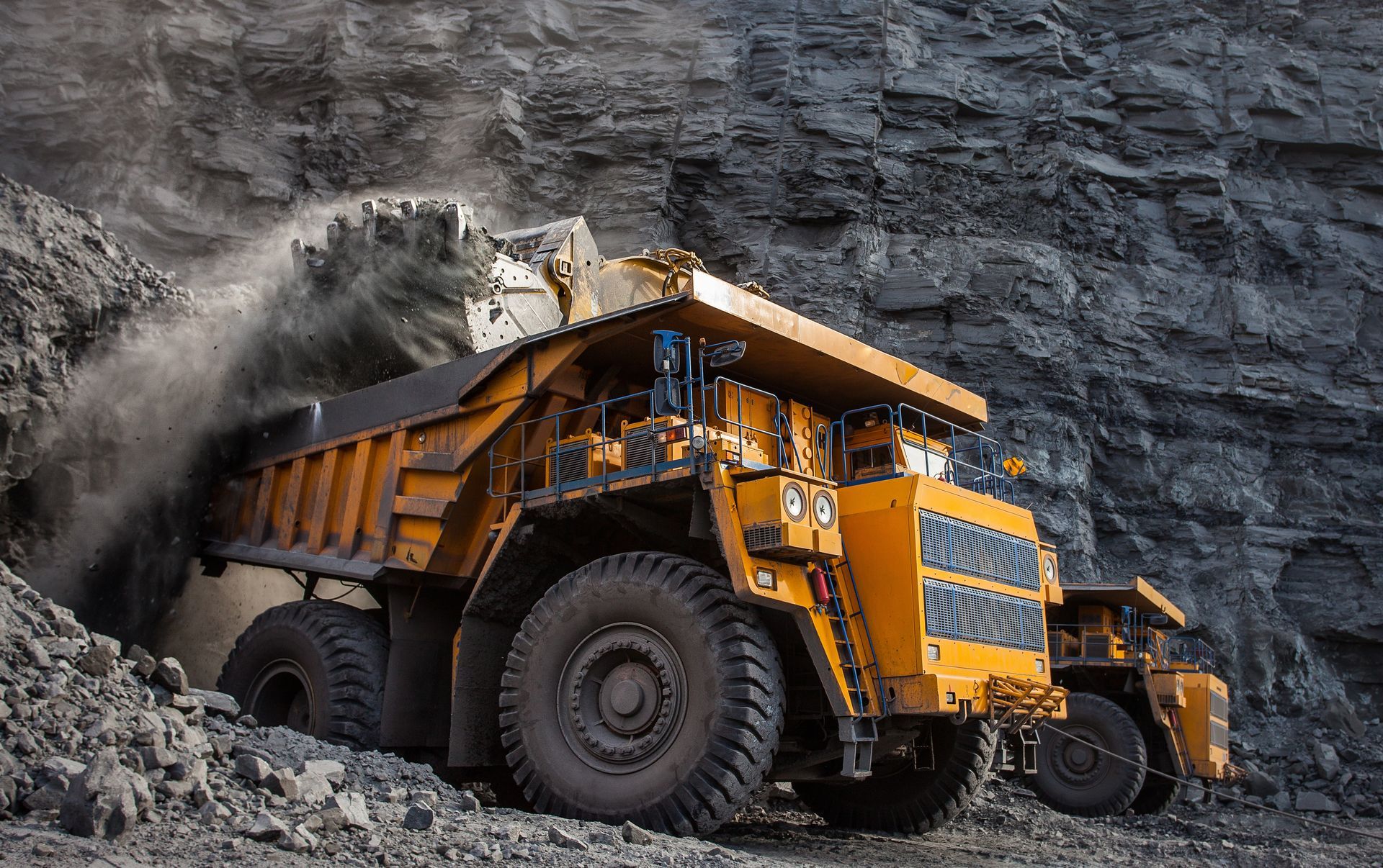 A yellow quarry mining truck in a coal mine loading coal.