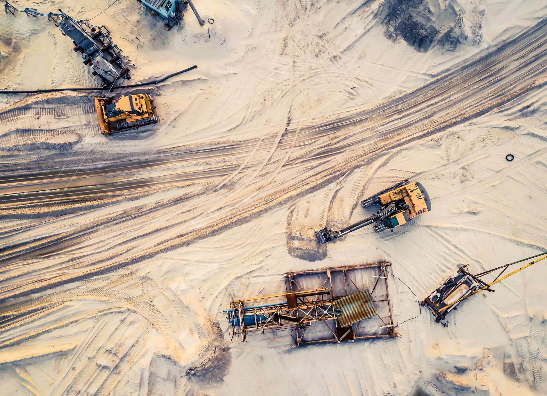 Aerial view of machinery and mine equipment near a road on a sandy surface