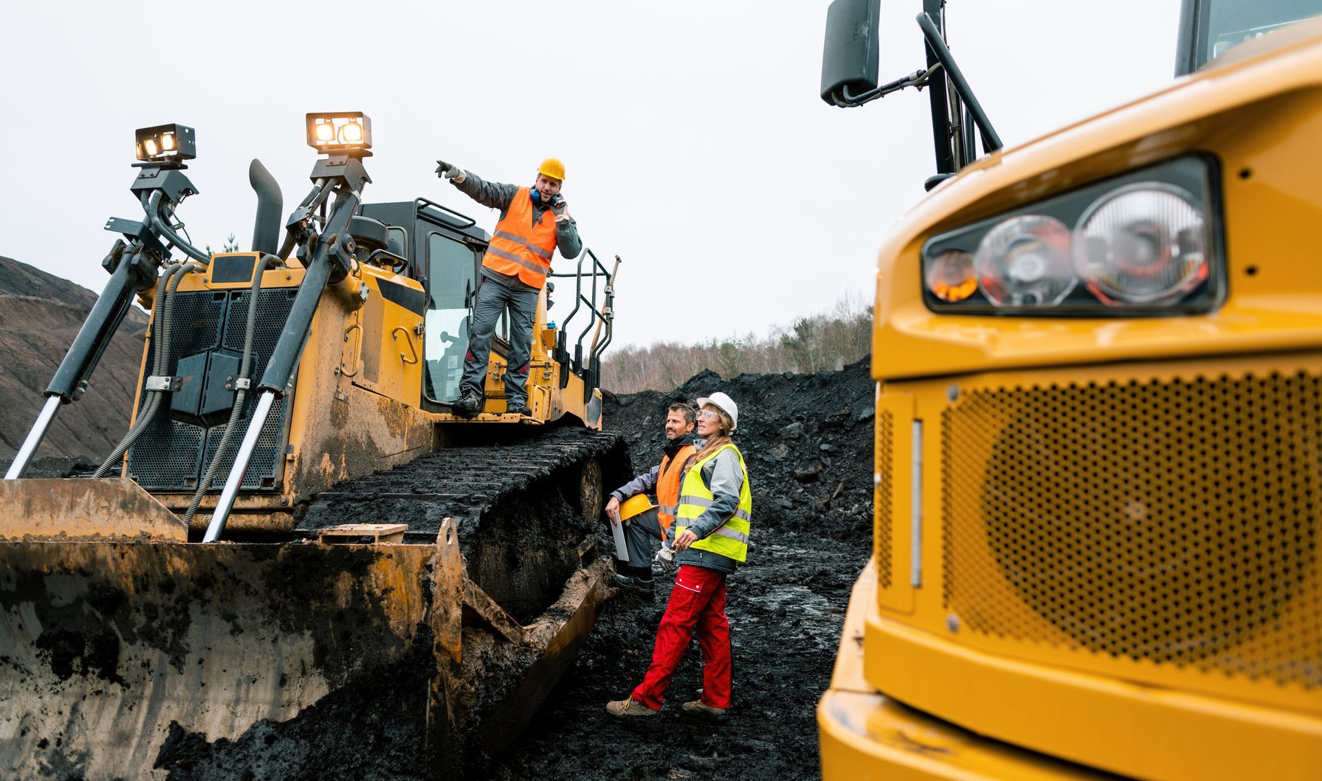 Heavy machinery and workers at a quarry pit, showcasing mining and construction equipment in use.