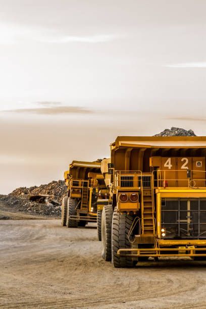 Dump trucks transporting platinum ore, showcasing mining and construction equipment in action.