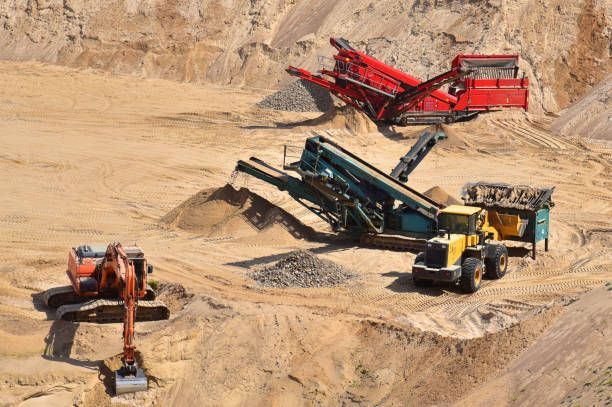 Excavator and conveyors working in a sand quarry.