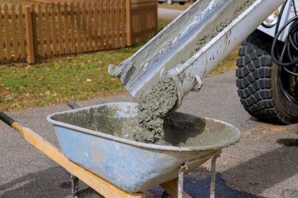 Cement from a mixer is being poured into a wheelbarrow, representing IMS pugmill services.