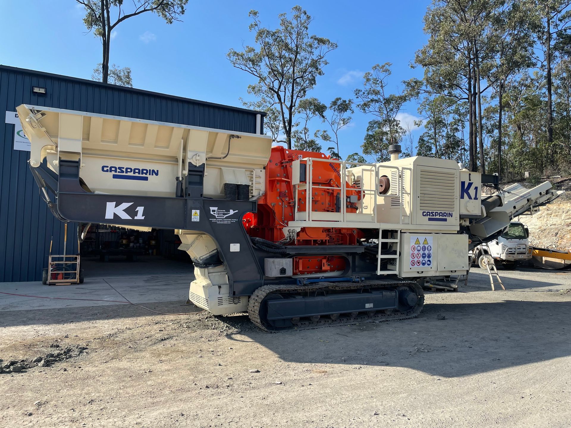 A large, beige and orange mobile rock crusher on tracks, labeled