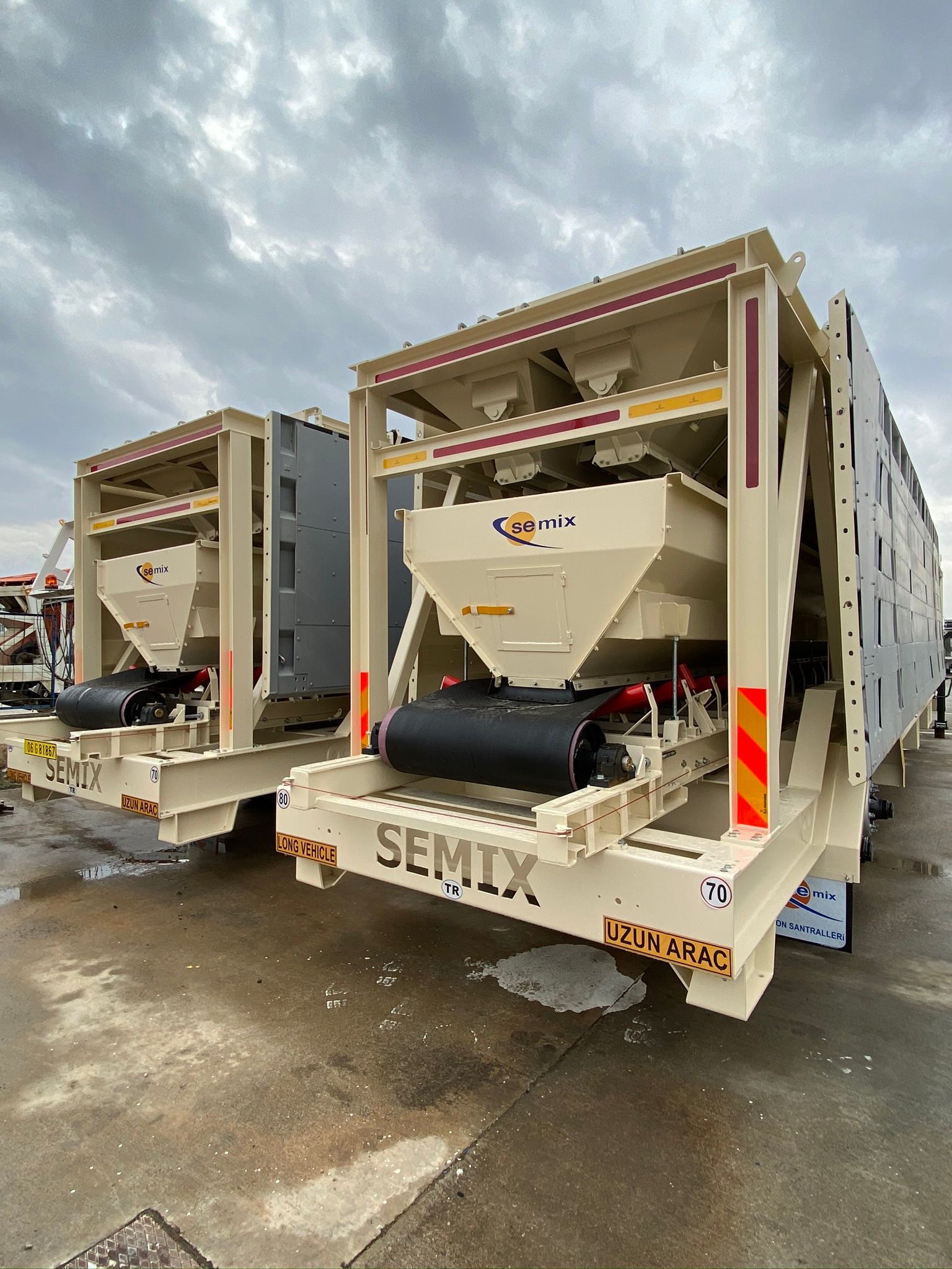 Two beige Semix concrete mixers sit outdoors under a cloudy sky. Each has a hopper, roller, and black components.