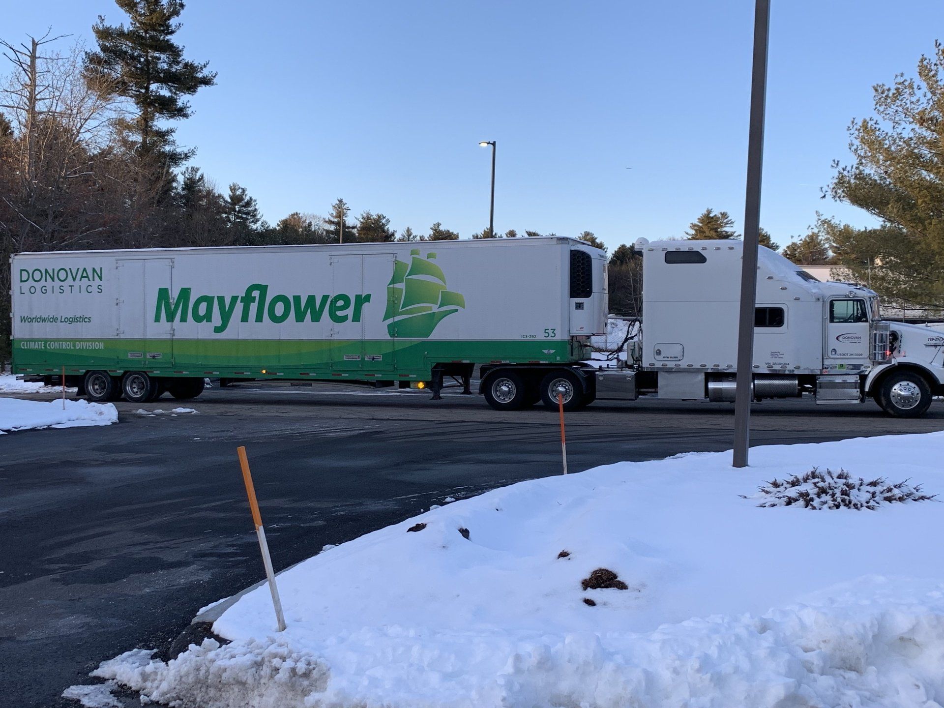 Mayflower moving truck parked on a snowy roadside under a clear blue sky