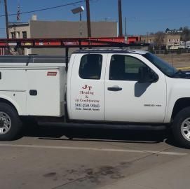 A white J.T. Heating & Air Conditioning utility truck parked in a sunny lot.