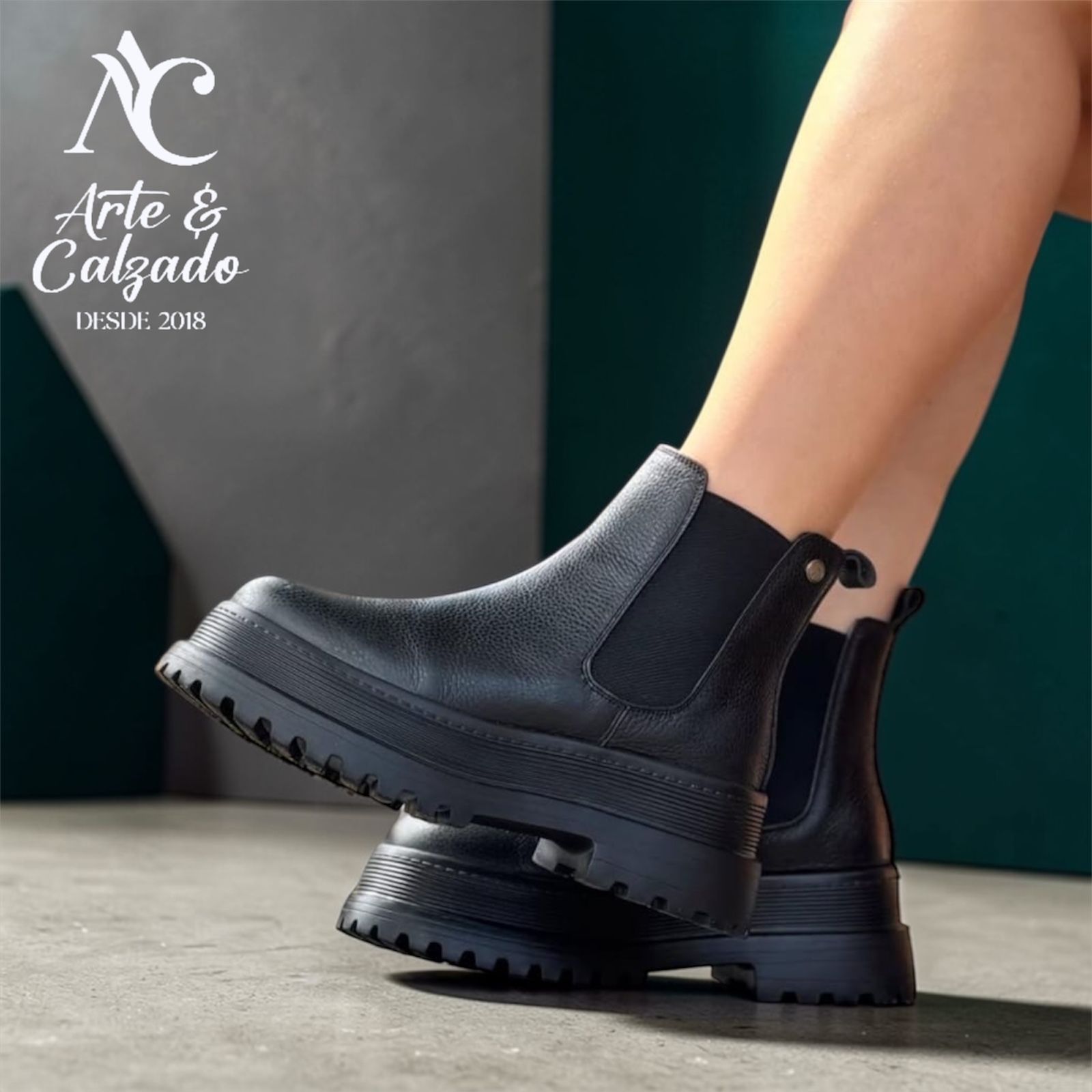 Un par de botas Chelsea negras con plataforma, usadas por una persona