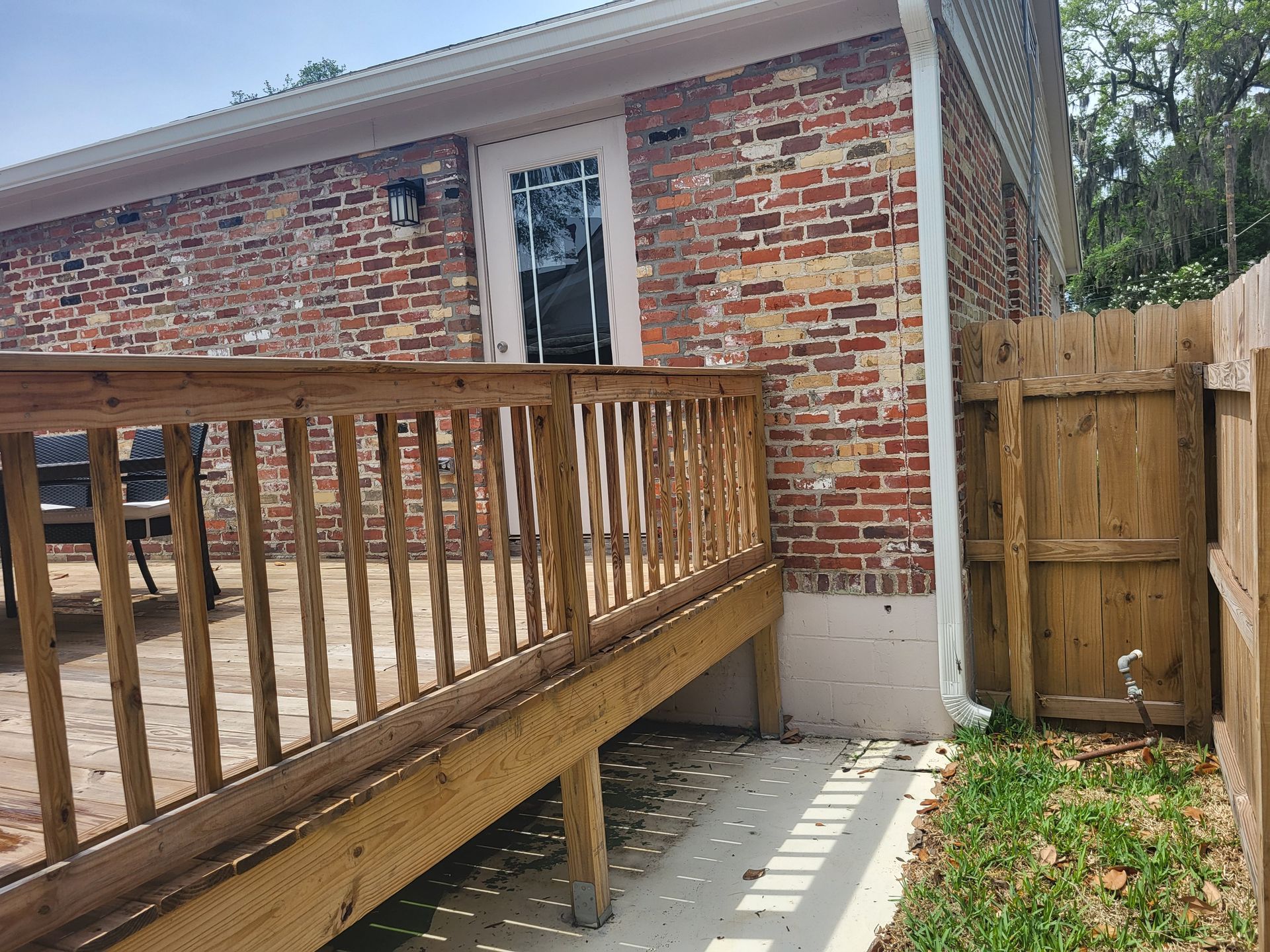 Wooden deck and brick building, with a wooden fence to the right.