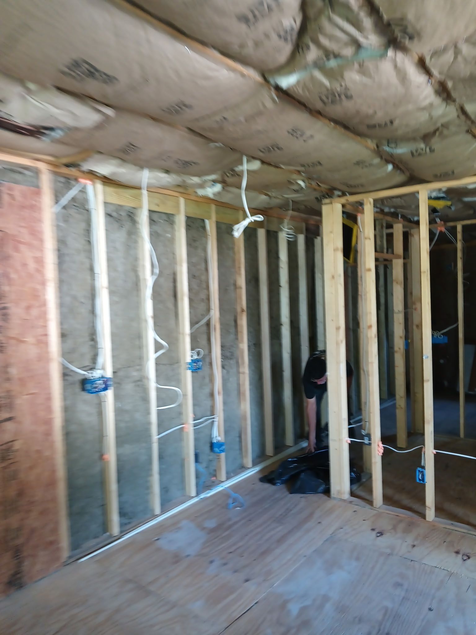 Interior of a room under construction with exposed wooden framing and electrical wiring.