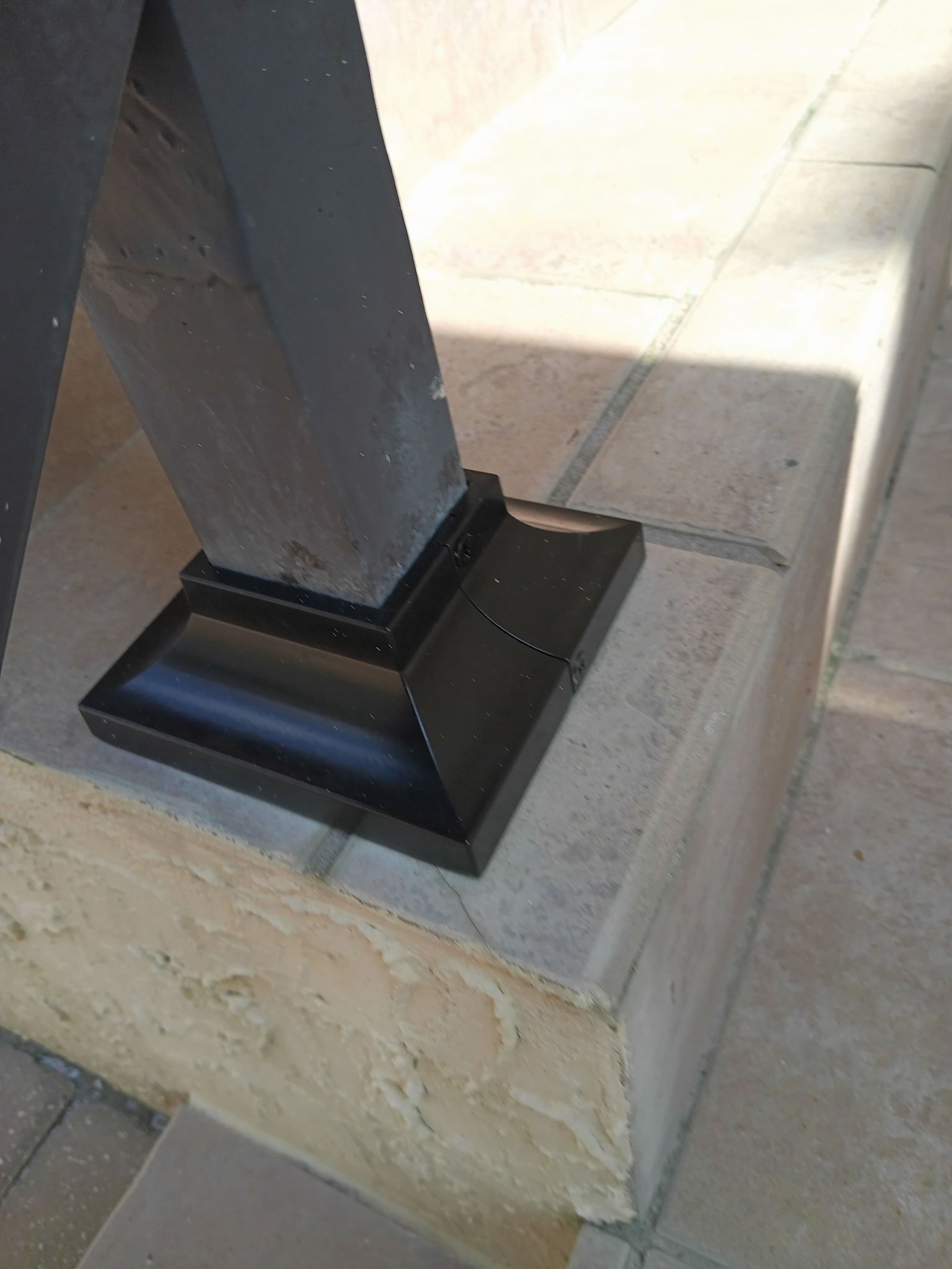 Black painted post base on a light stone step.