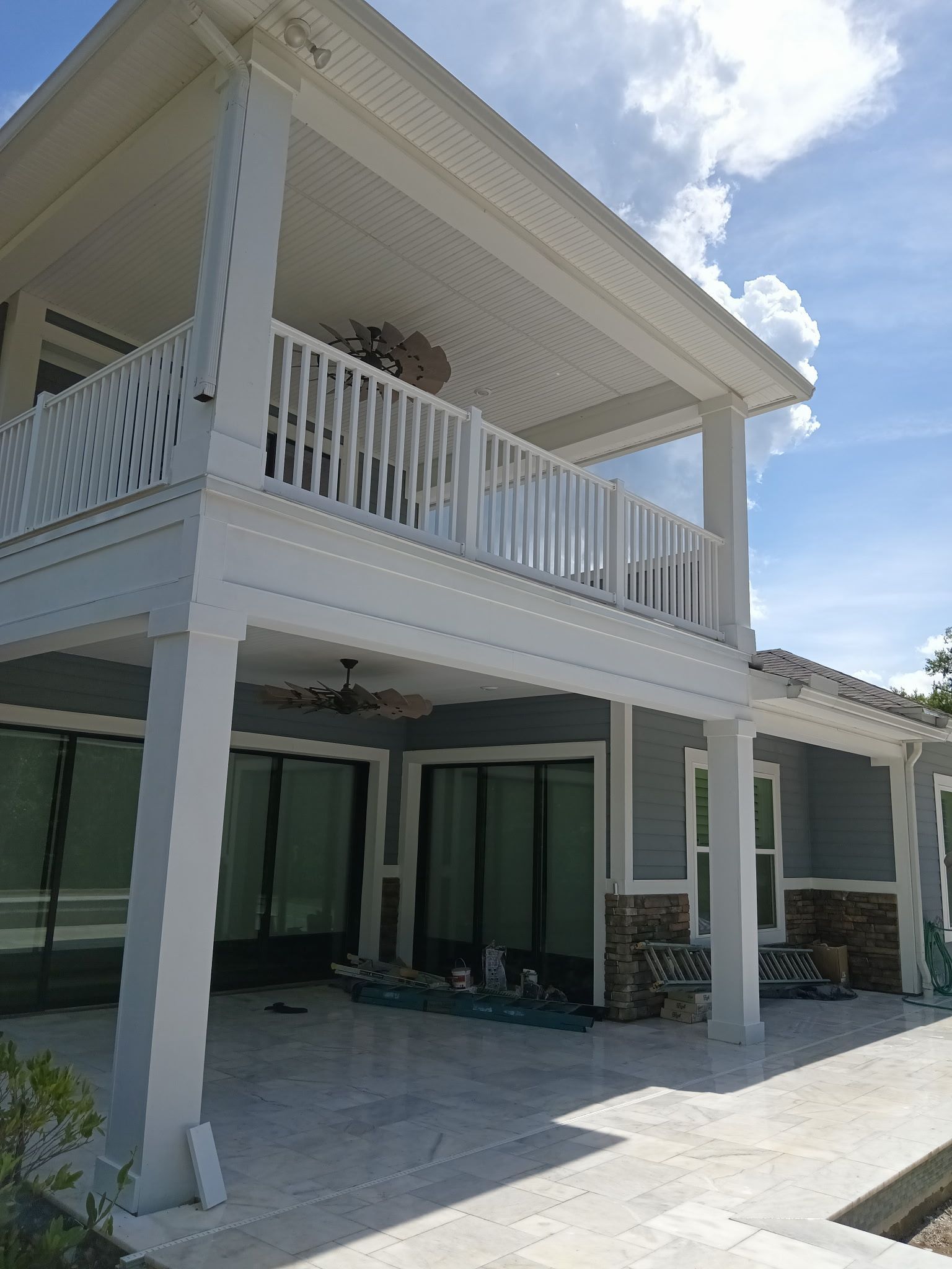 Two-story house with a porch and balcony; blue siding, white trim, and clear skies.