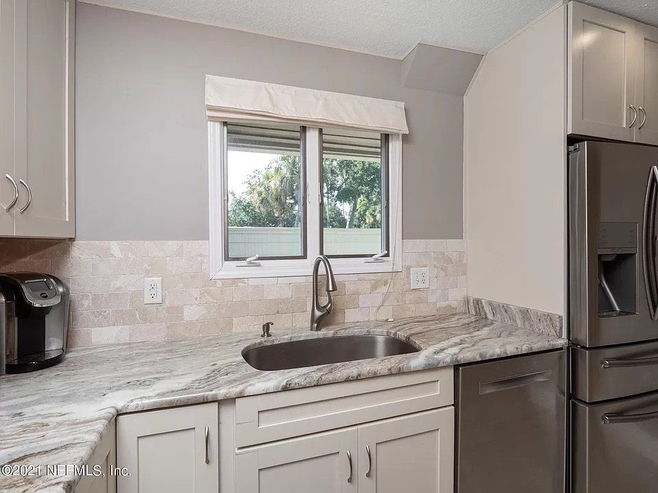 Kitchen with granite countertops, stainless steel sink, and light gray cabinets.