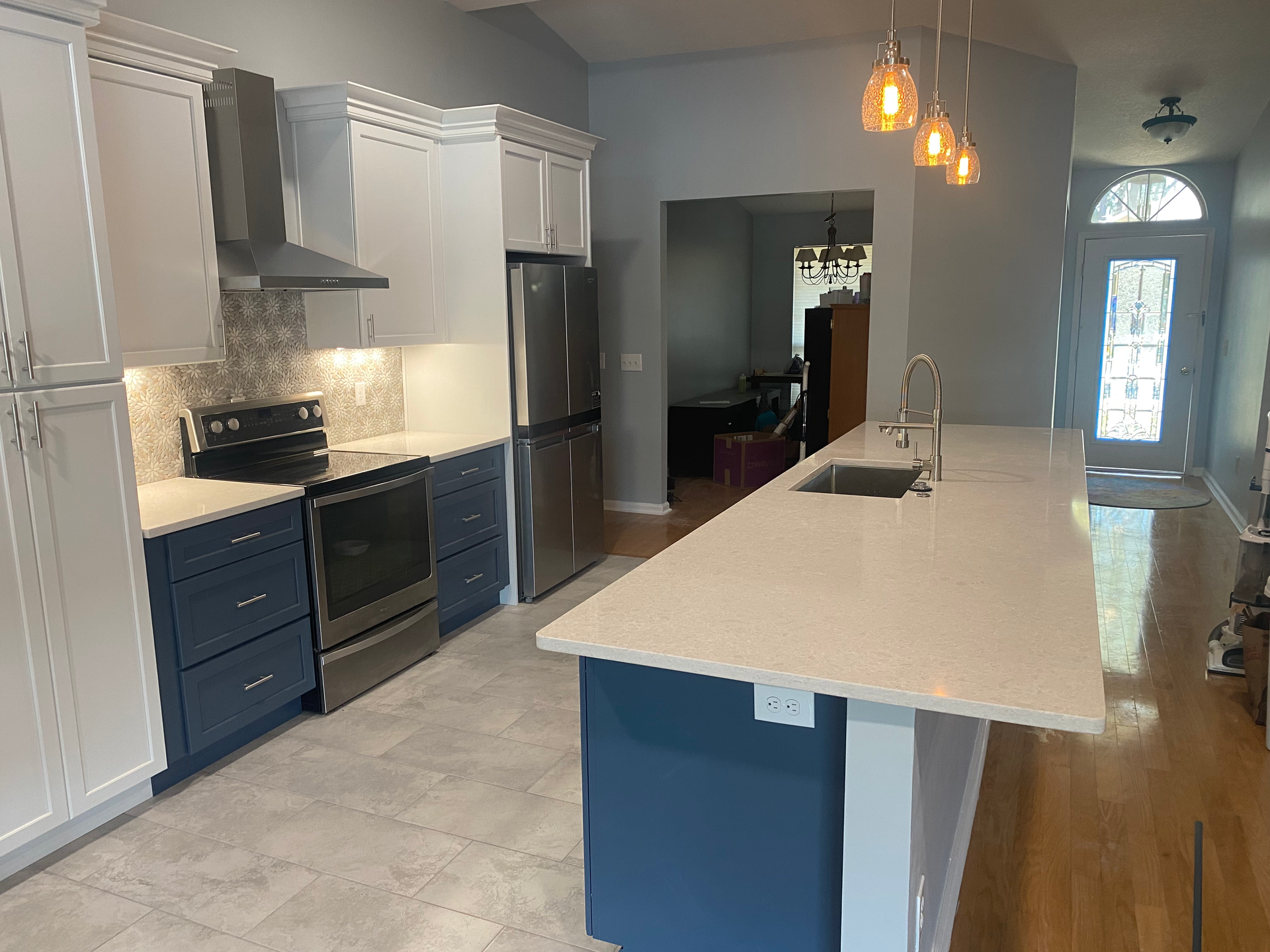 Modern kitchen with white and blue cabinets, stainless steel appliances, and a large island.