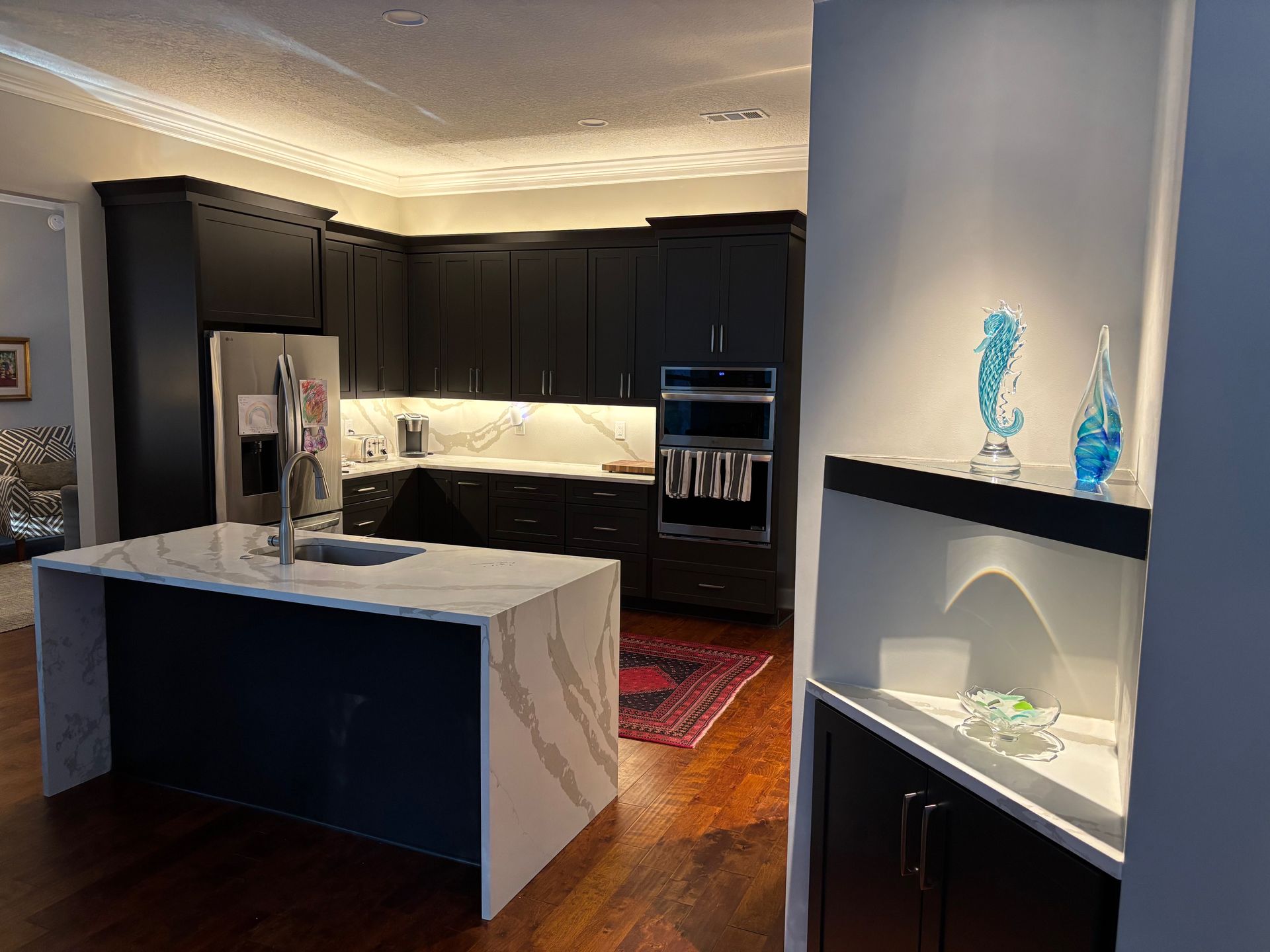 Modern kitchen with black cabinets, white countertops, and an island. Includes a seahorse decoration.