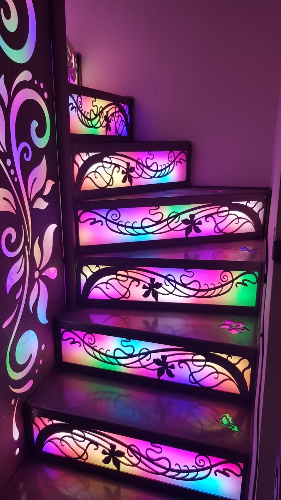 Una scala con alzate illuminate caratterizzate da vivaci sfumature multicolori e intricati motivi floreali scuri.