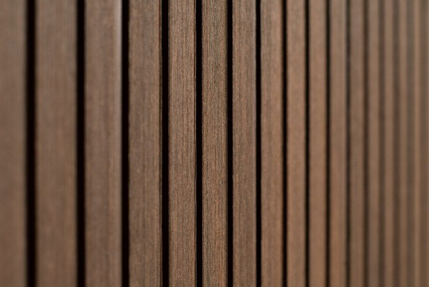Vista ravvicinata di listelli di legno verticali di colore marrone scuro, disposti secondo uno schema ripetitivo.