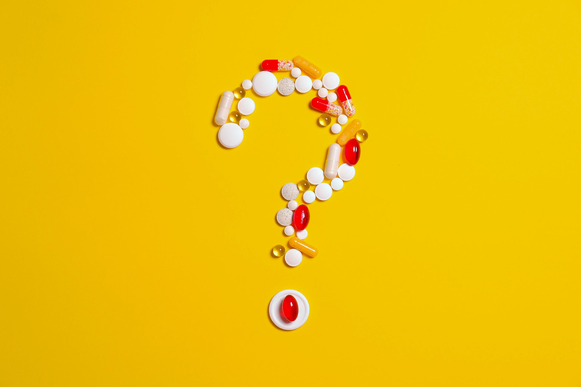 A question mark made out of pills on a yellow background