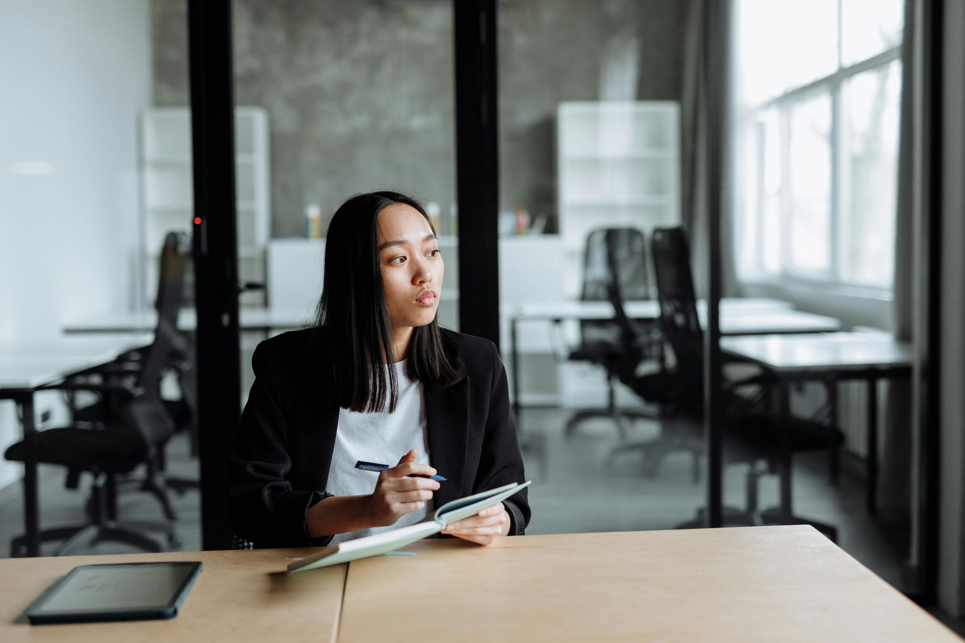 A woman taking notes, thinking, looking out the window