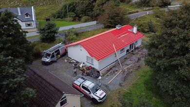 A van is parked in front of a house with solar panels on the roof.