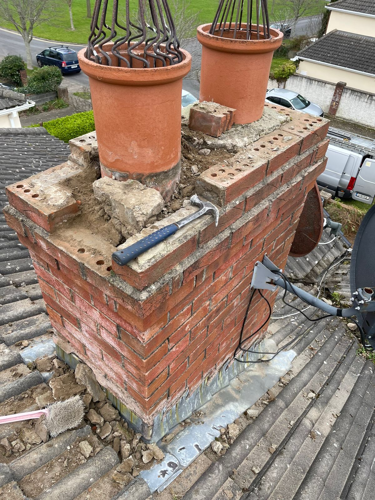 A hammer is sitting on top of a brick chimney.