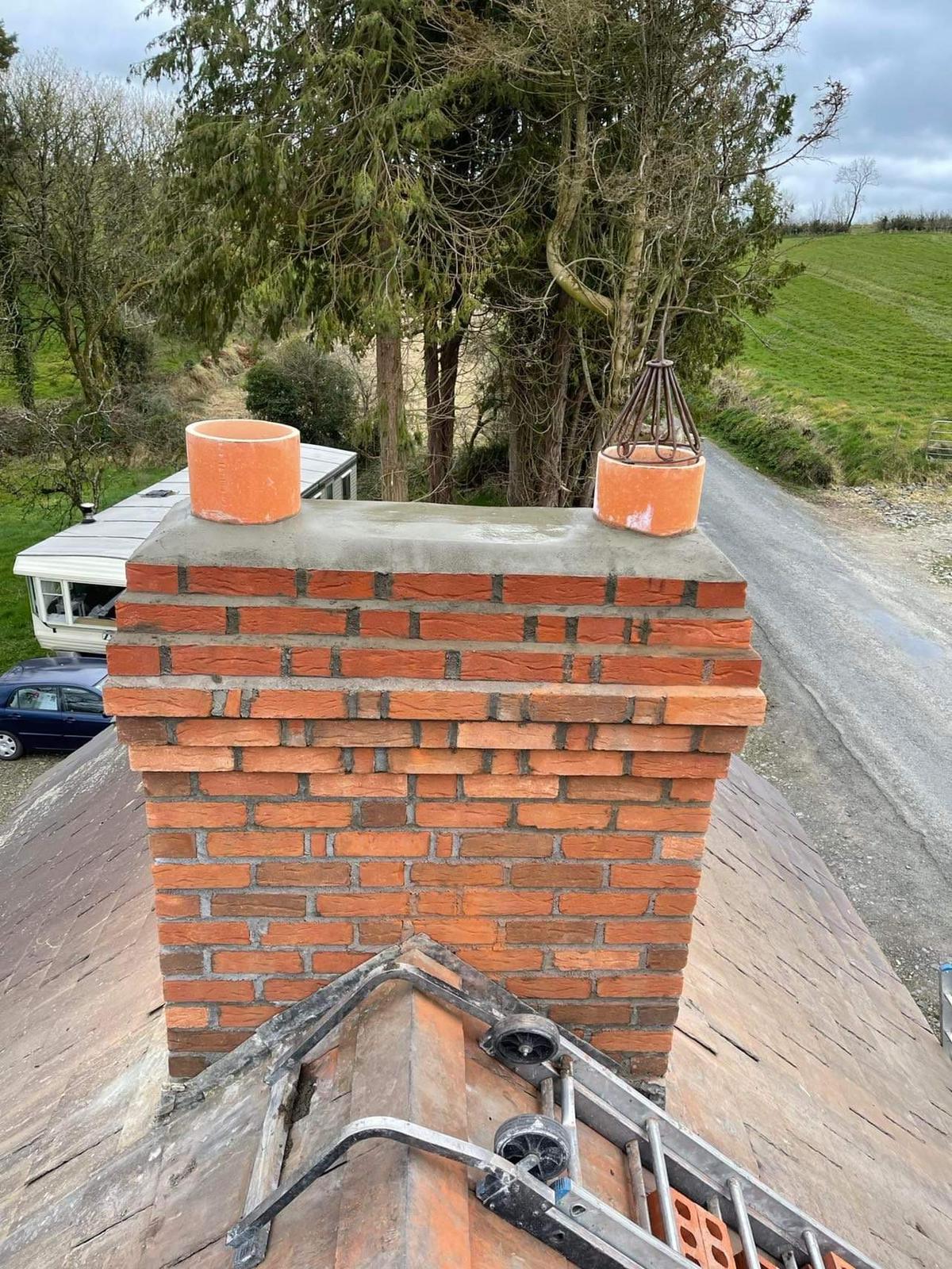 A brick chimney on top of a roof with a ladder attached to it.