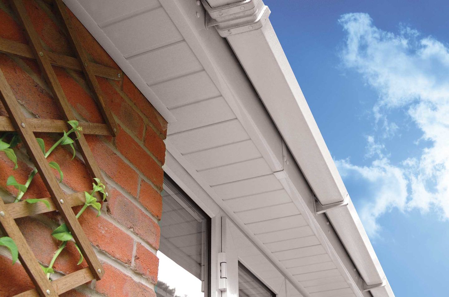 A white gutter is hanging from the side of a brick building.
