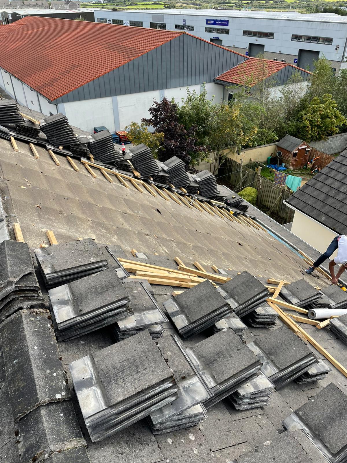 A roof with a lot of tiles on it and a building in the background.