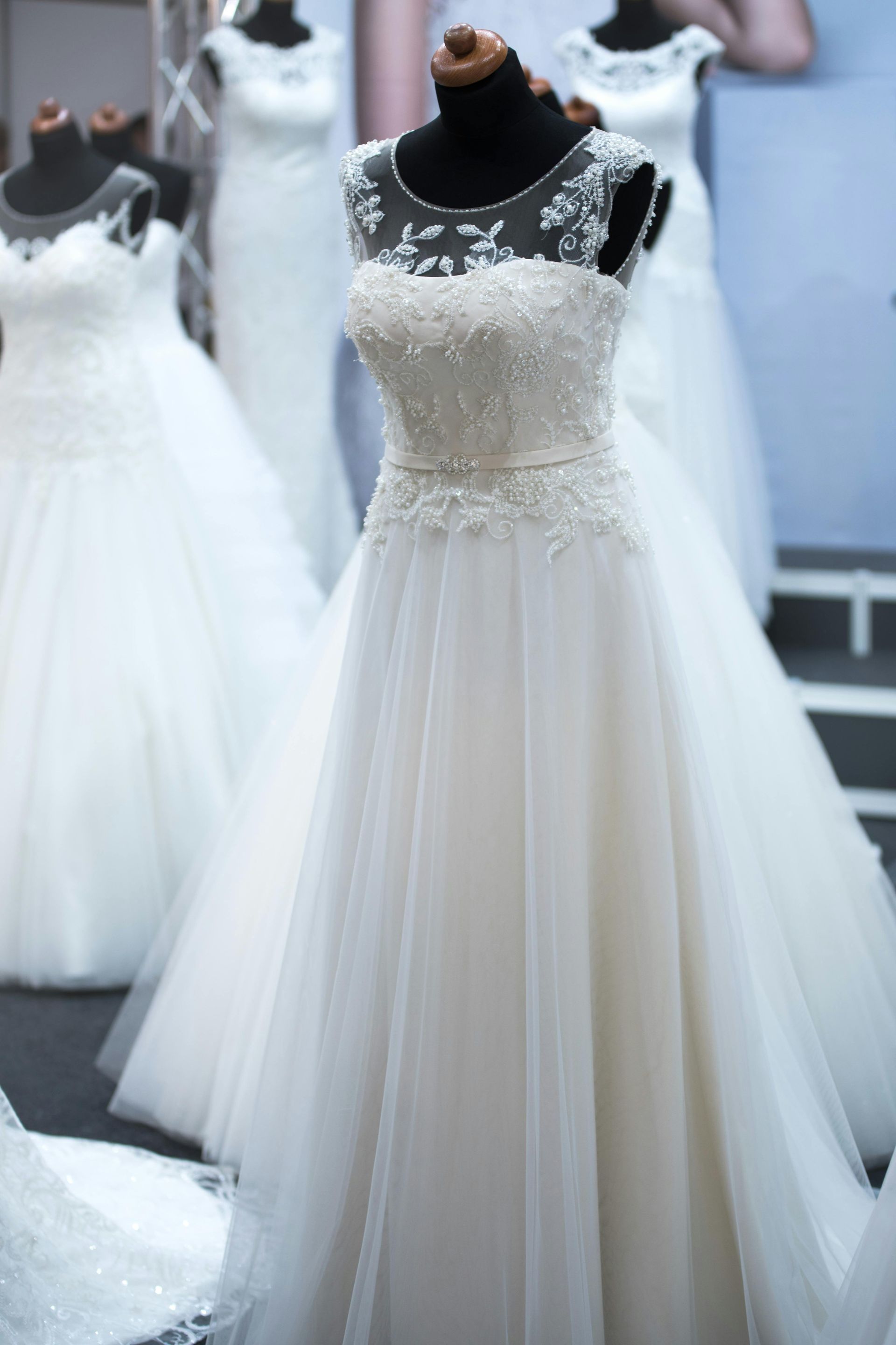Multiple white wedding dresses displayed on mannequins in a bridal boutique.