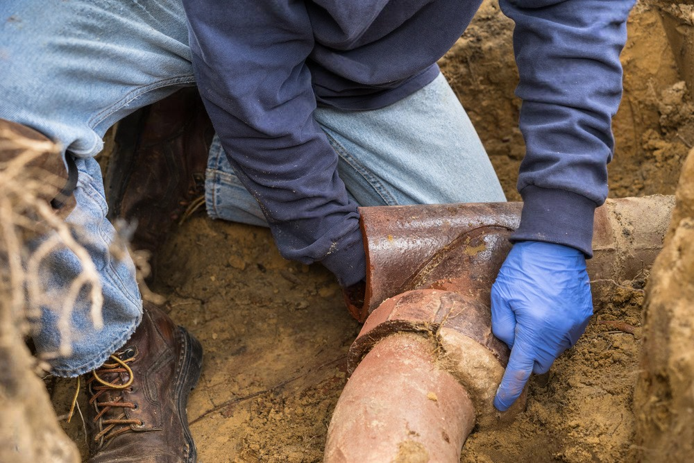 a man wearing blue gloves is working on a rusty pipe