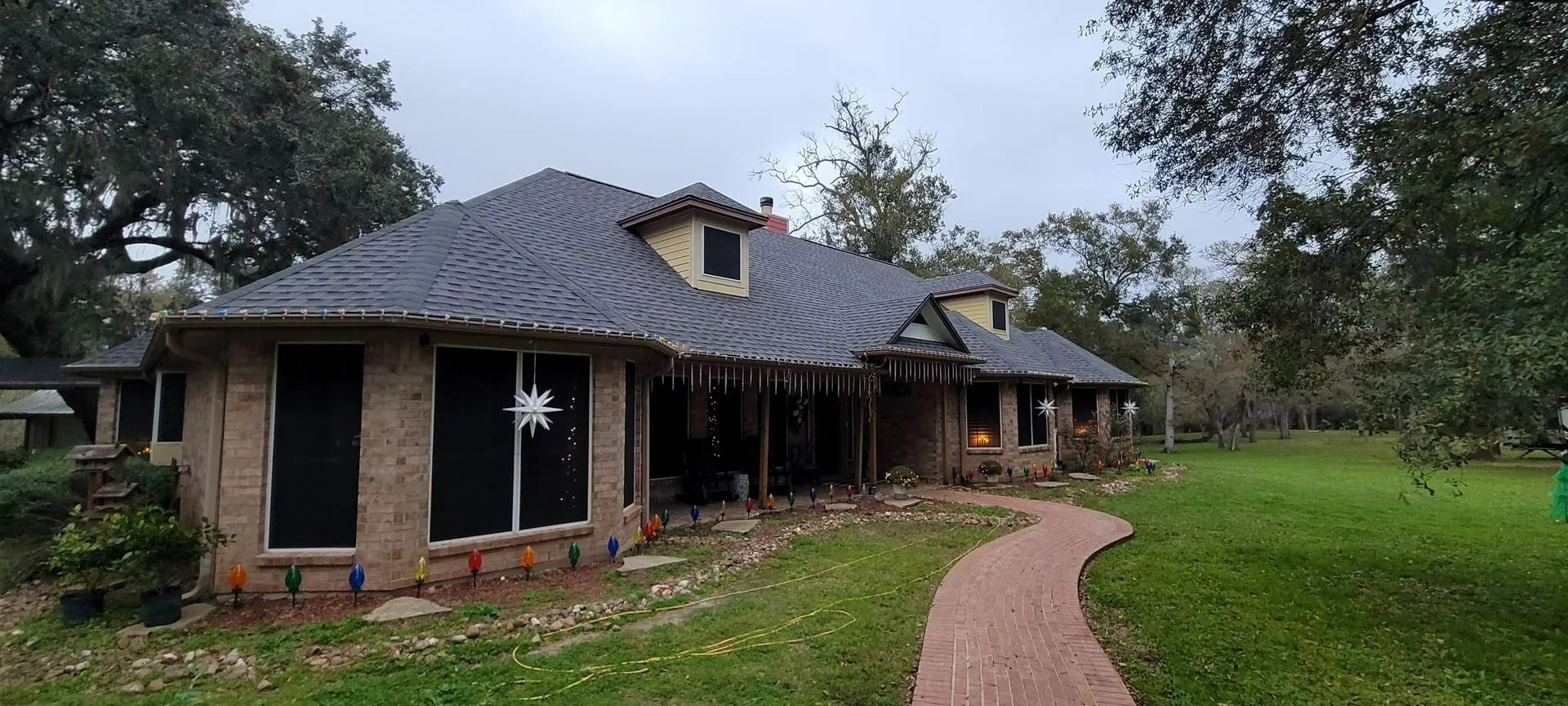 House with a brick exterior and a dark roof; a brick pathway leads to the front door.