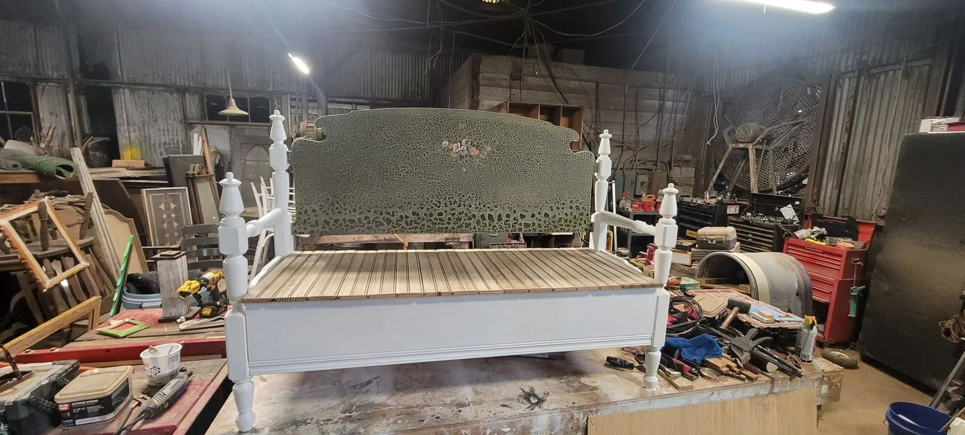 White bed frame in a cluttered workshop.