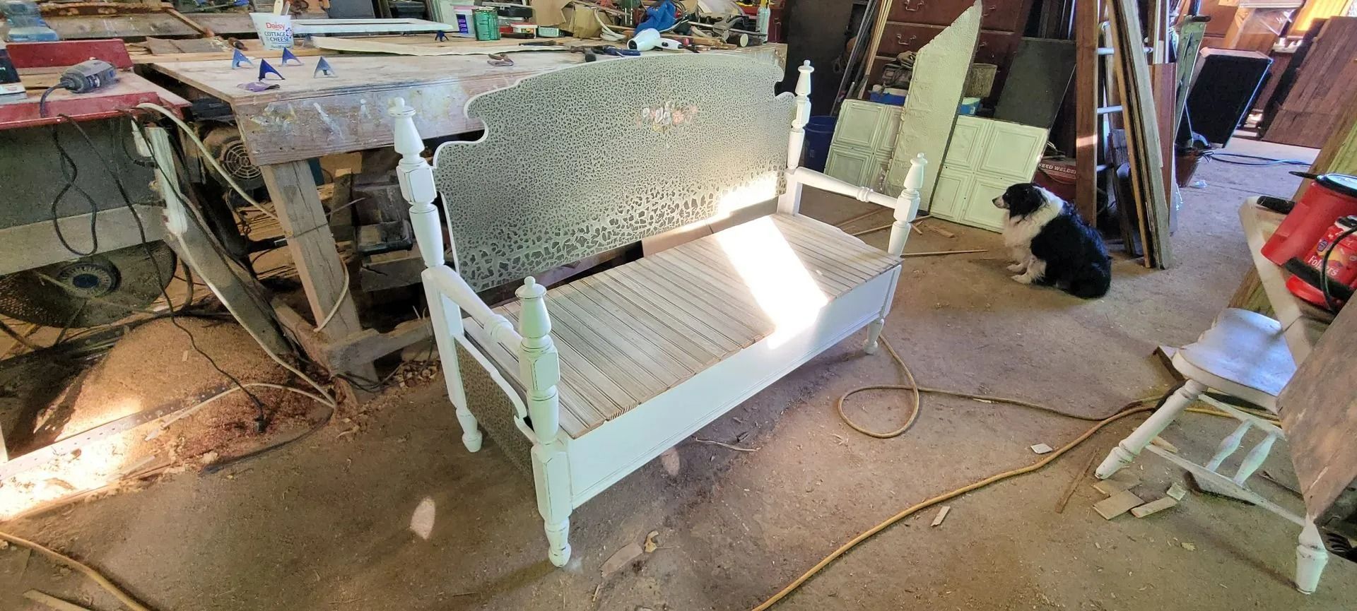 White painted bench in workshop with dog in background.