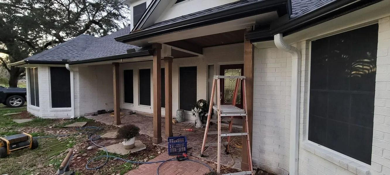 Exterior of a house with a porch under construction, ladder and tools present.