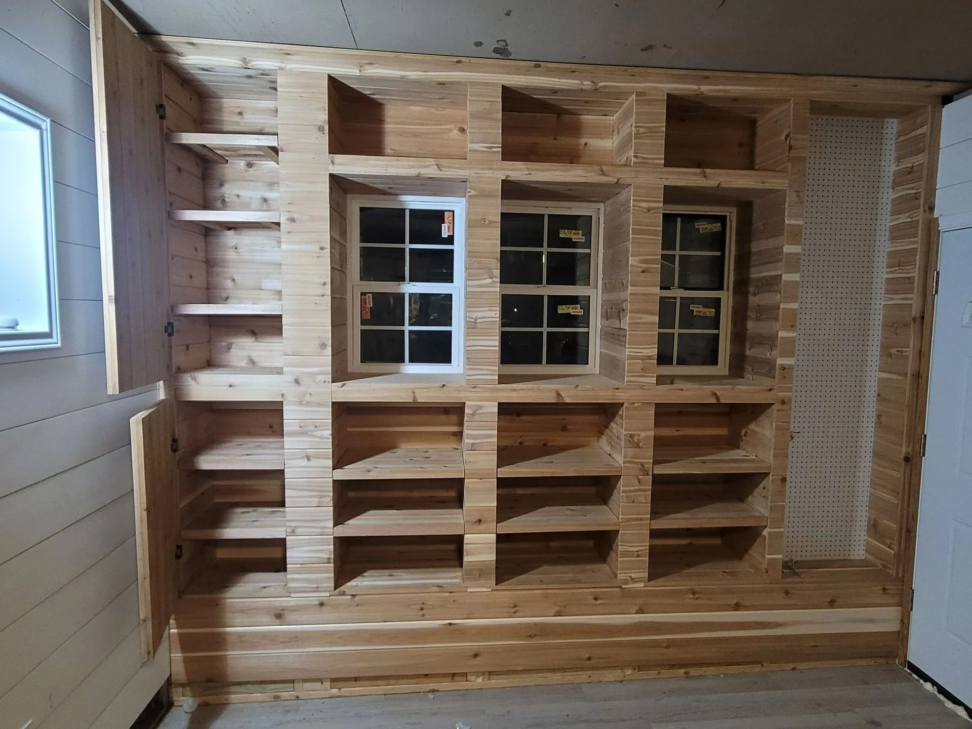 Built-in wooden shelving unit with window frames. Unfinished wood in a room.