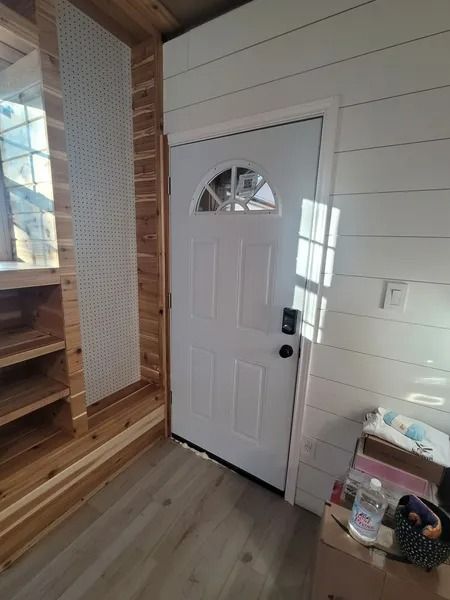 White door with arched window, inside a small space with wood and white walls.