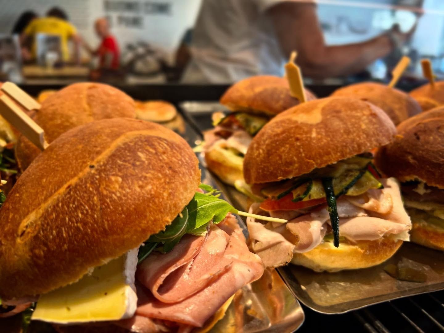 Panini su un vassoio; ripieni assortiti su panini croccanti. Sfondo sfocato dell'interno di un bar.