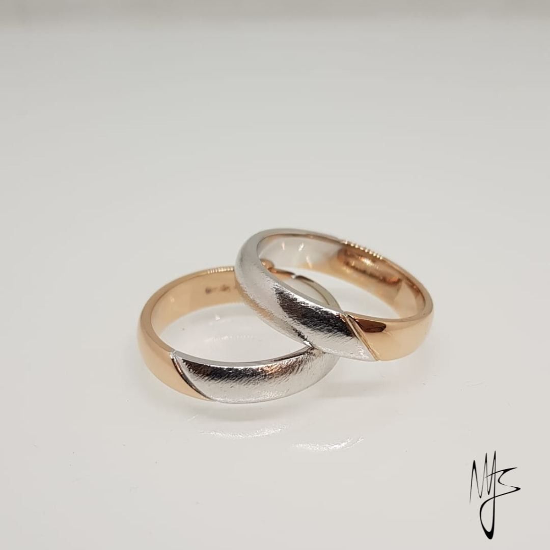 Due fedi nuziali, una d'oro e una d'oro e argento, adagiate su una superficie bianca.