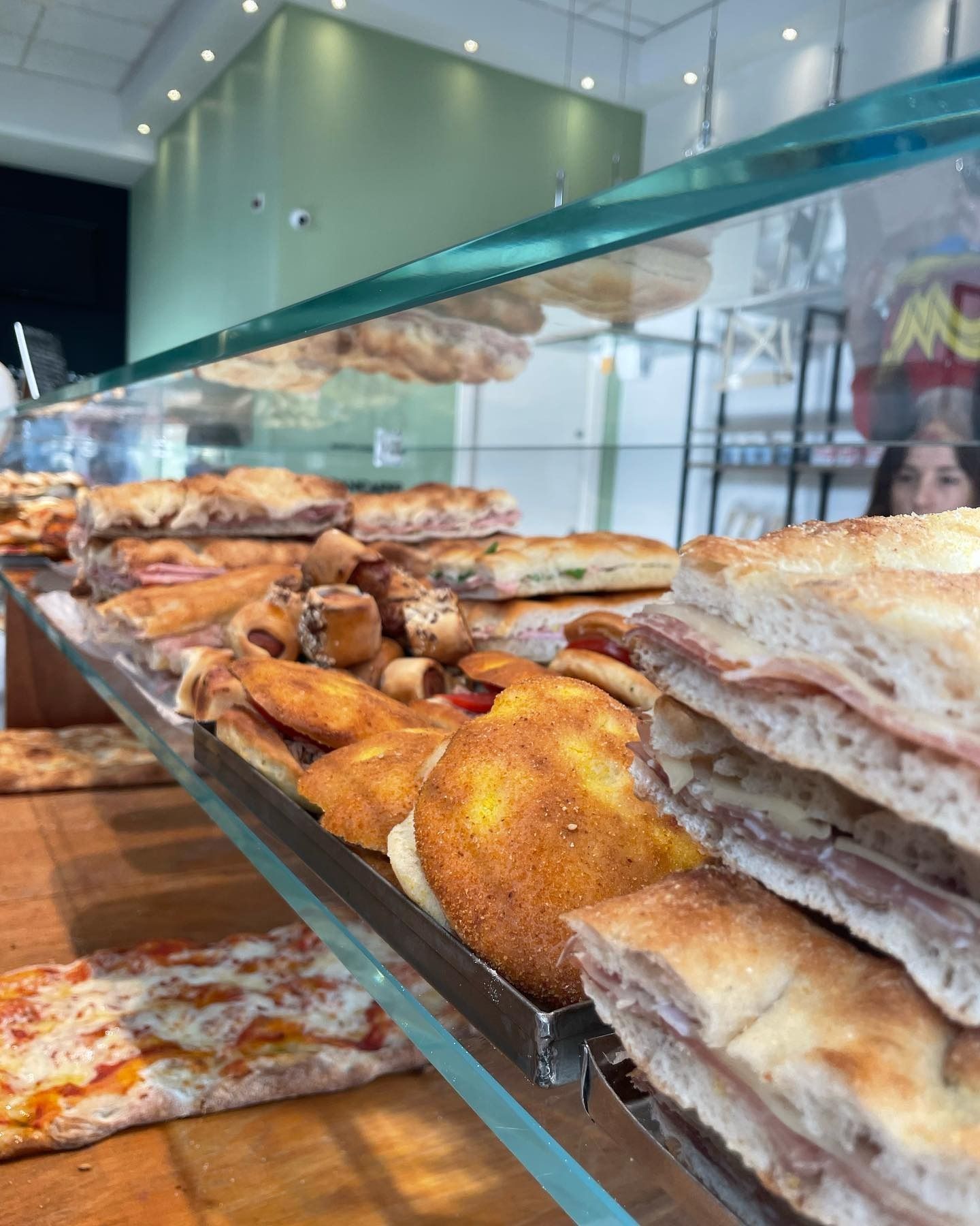 Vetrina con vari prodotti da forno, tra cui panini e pizza. Interno ben illuminato.