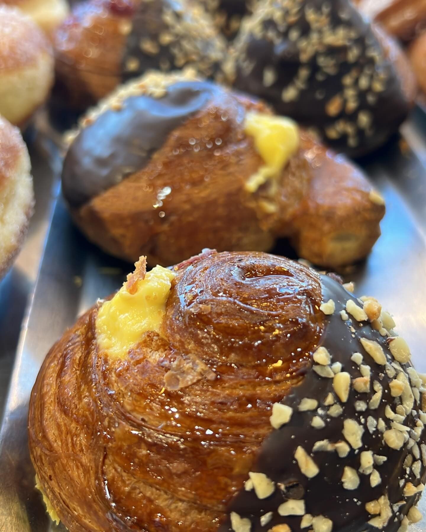 Pasticcini con glassa al cioccolato, noci e ripieno di crema su un vassoio.
