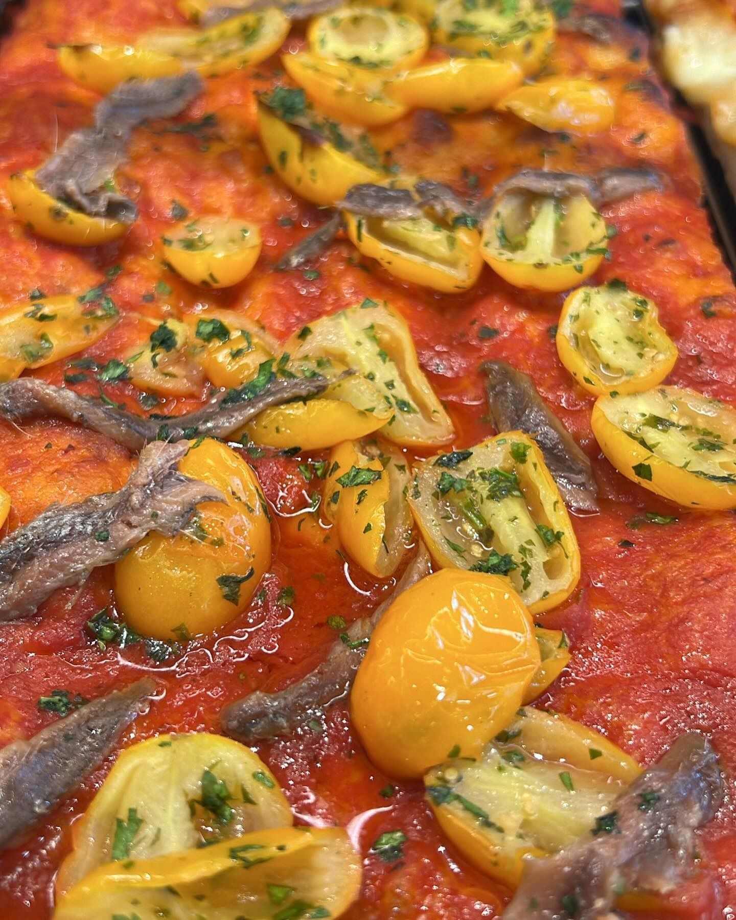 Esposizione di croissant spolverati con zucchero a velo, in un ambiente da panetteria con un utensile da portata.