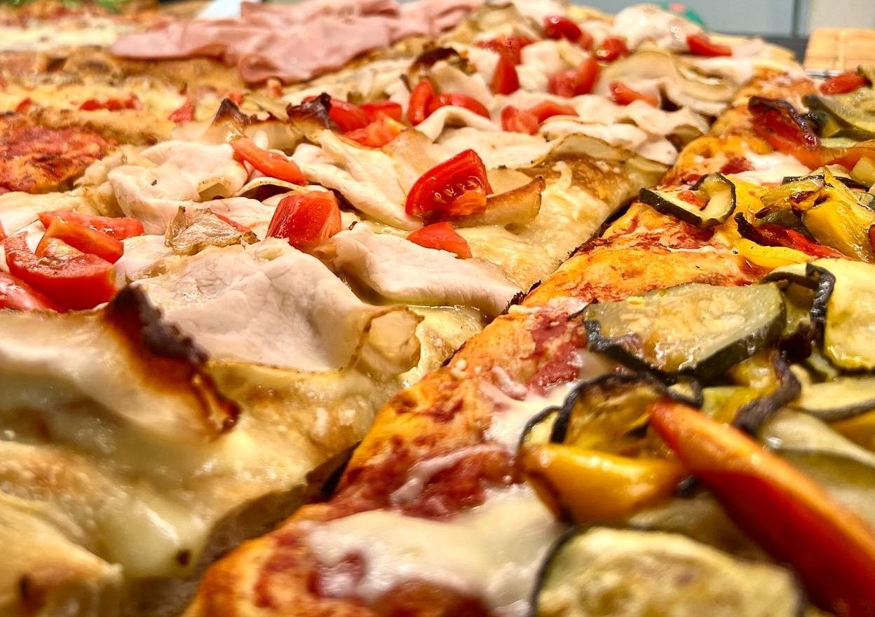 Biscotti con gocce di cioccolato e granella, disposti su un vassoio, con le pinze in primo piano.