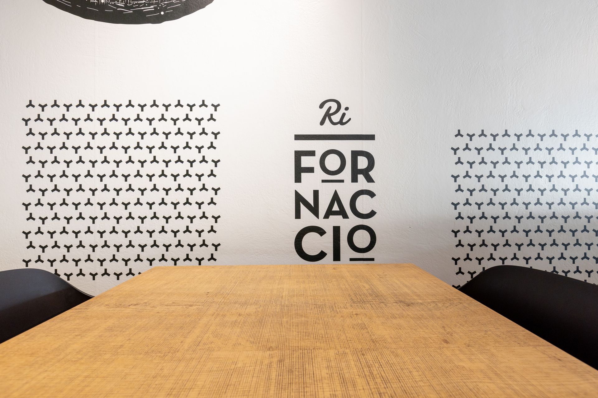 Tavolo in legno davanti a una parete con disegni neri e la scritta 